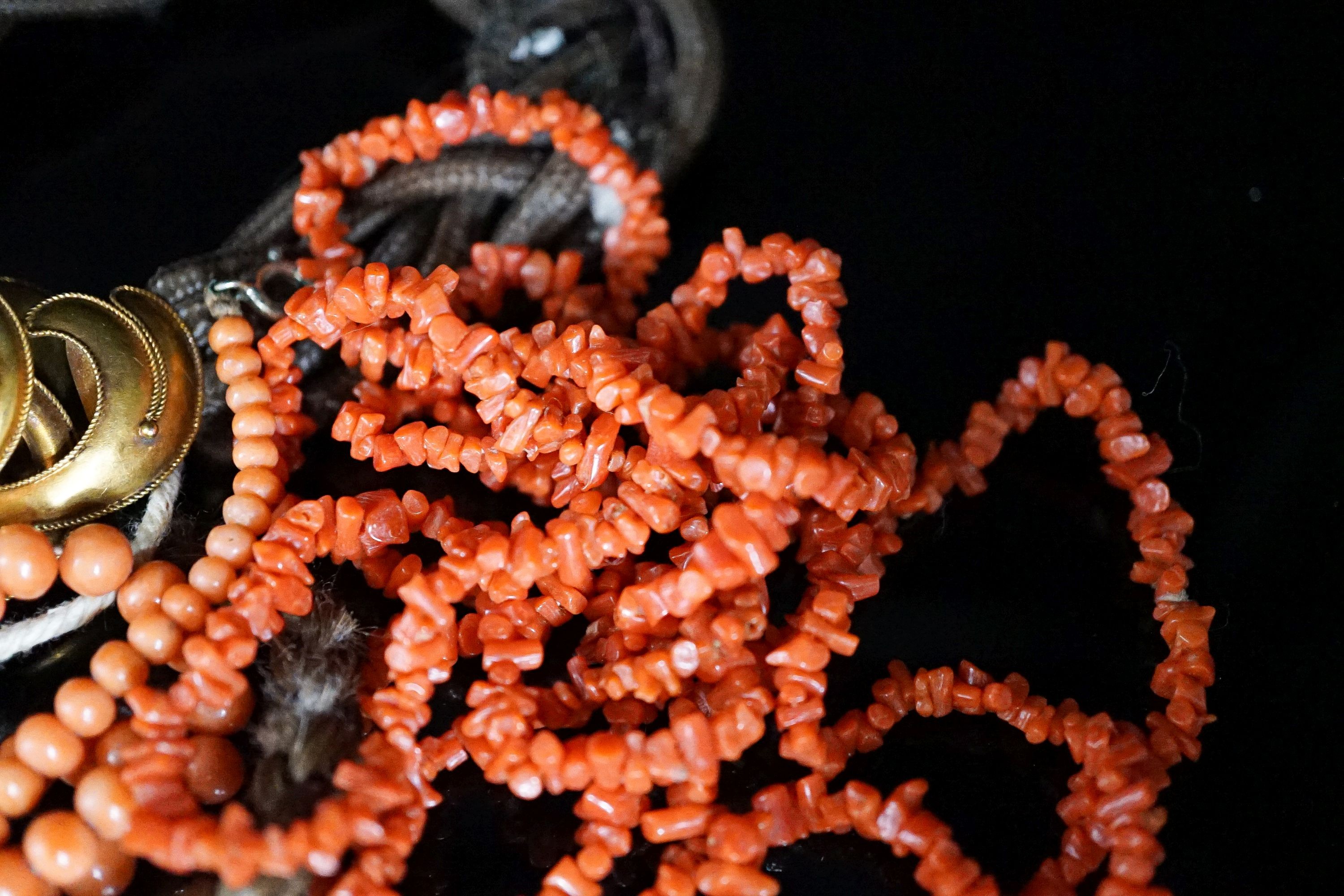 A Victorian yellow metal mounted hairwork bracelet, hung with plaited hair tassel with yellow metal fob, and two coral necklaces.